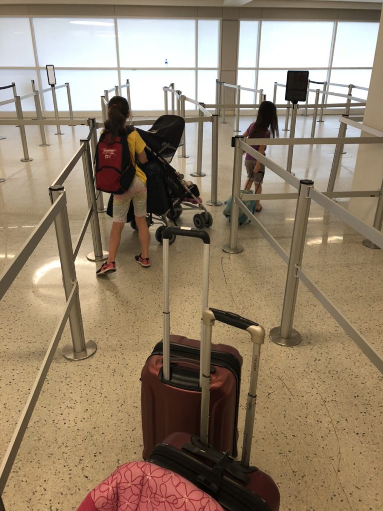 young girl pushes a stroller through airport lines