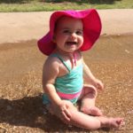 Baby splashes with a pink swim hat on