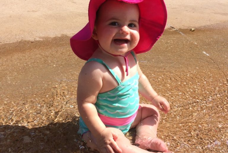Baby splashes with a pink swim hat on