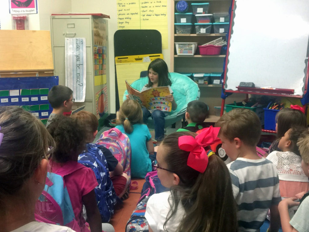 A girl reading to her kindergarten class after mom teaches her to read