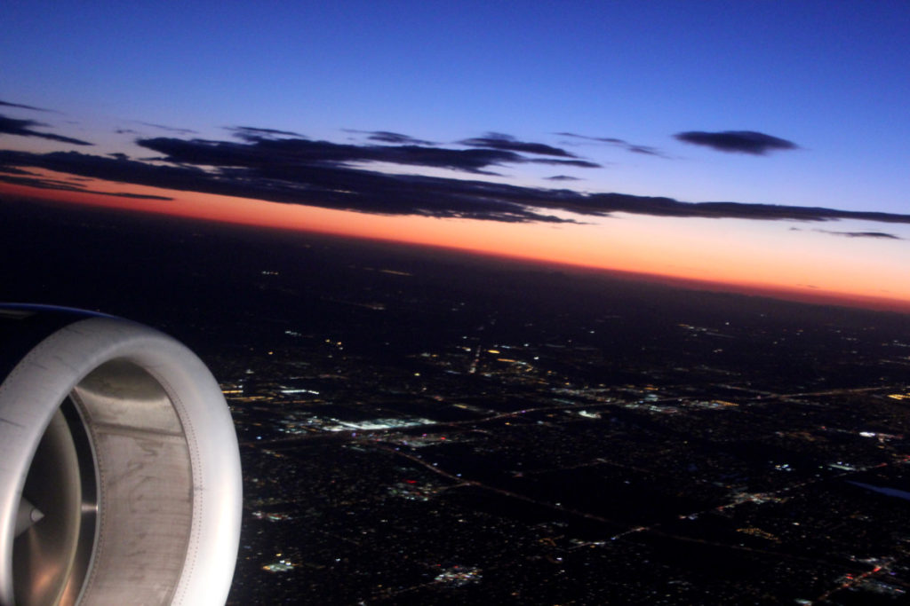 An Airplane Jet engine in a blue and orange sunset over a city