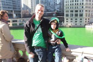 a man and his son in front of the river dyed green in Chicago Illinois