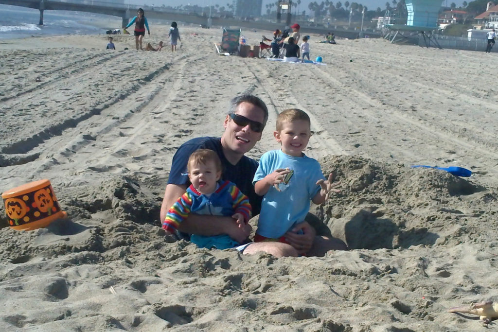 a Dad and 2 children in a hole at Newport Beach, California 