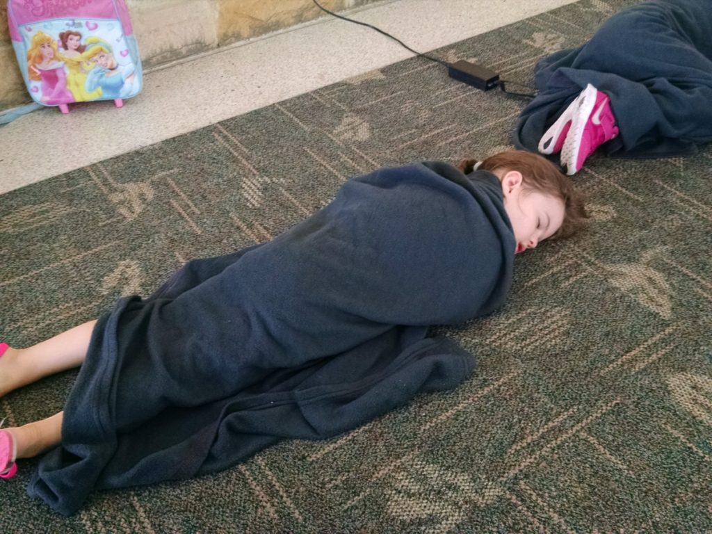 A girl naps on the airport floor