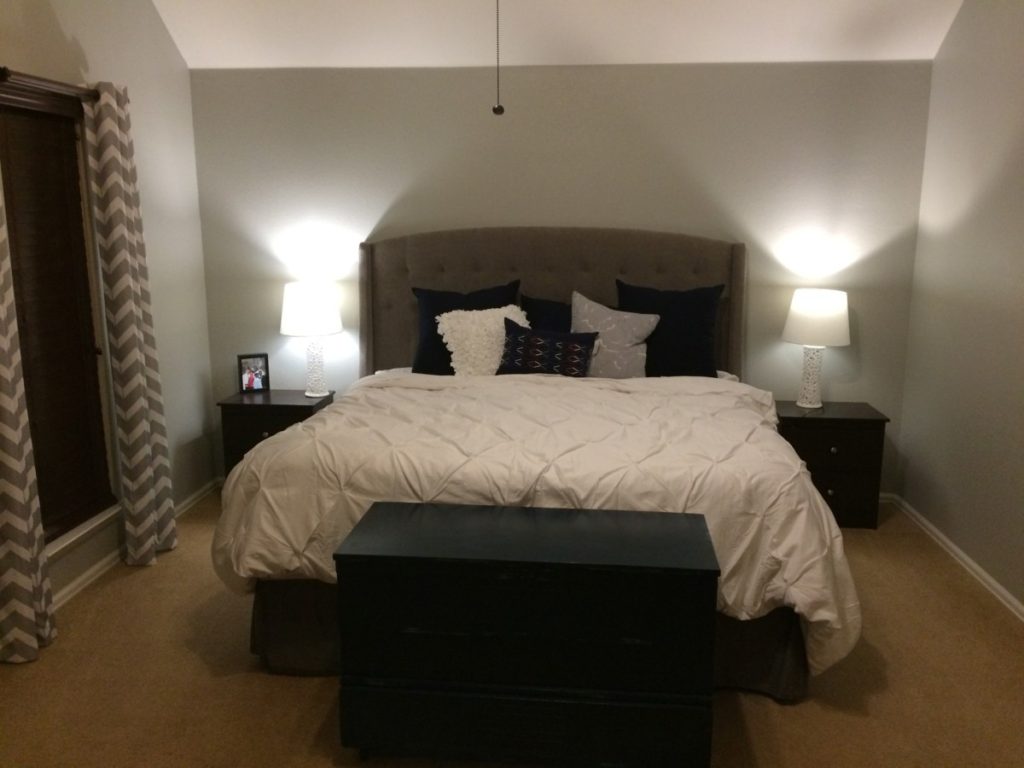 master bedroom wit white duvet cover and navy and gray pillows