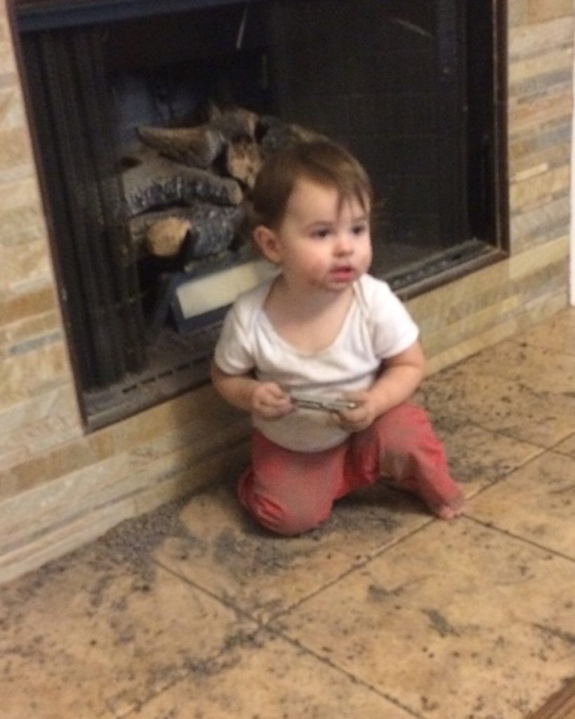 A toddler plays in the fireplace dirt