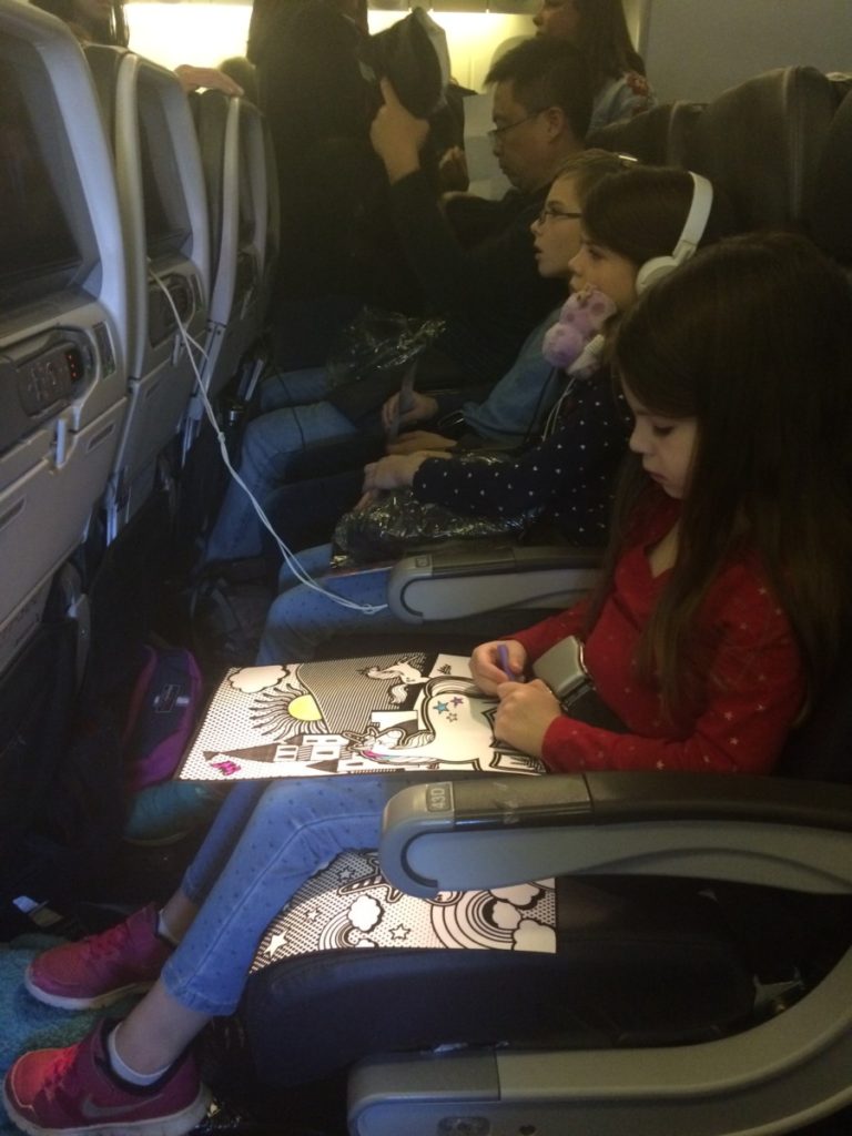 3 kids entertaining themselves on a plane