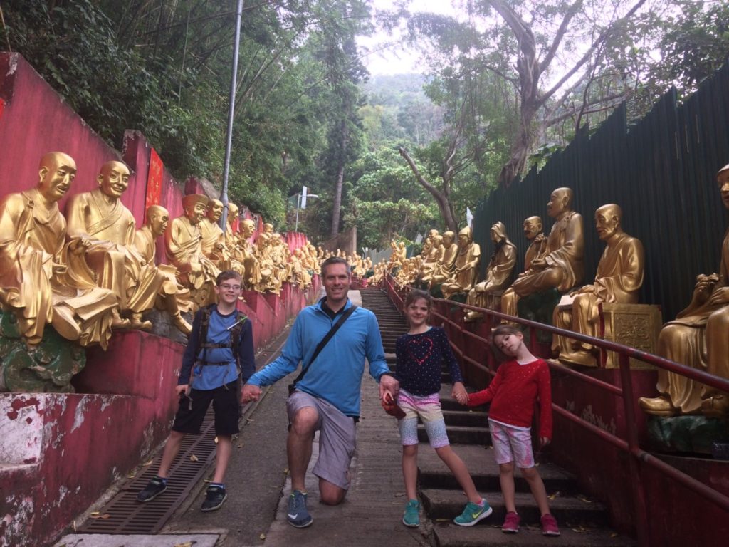 A dad with 3 kids hold hands across the trail of 10000 buddhas