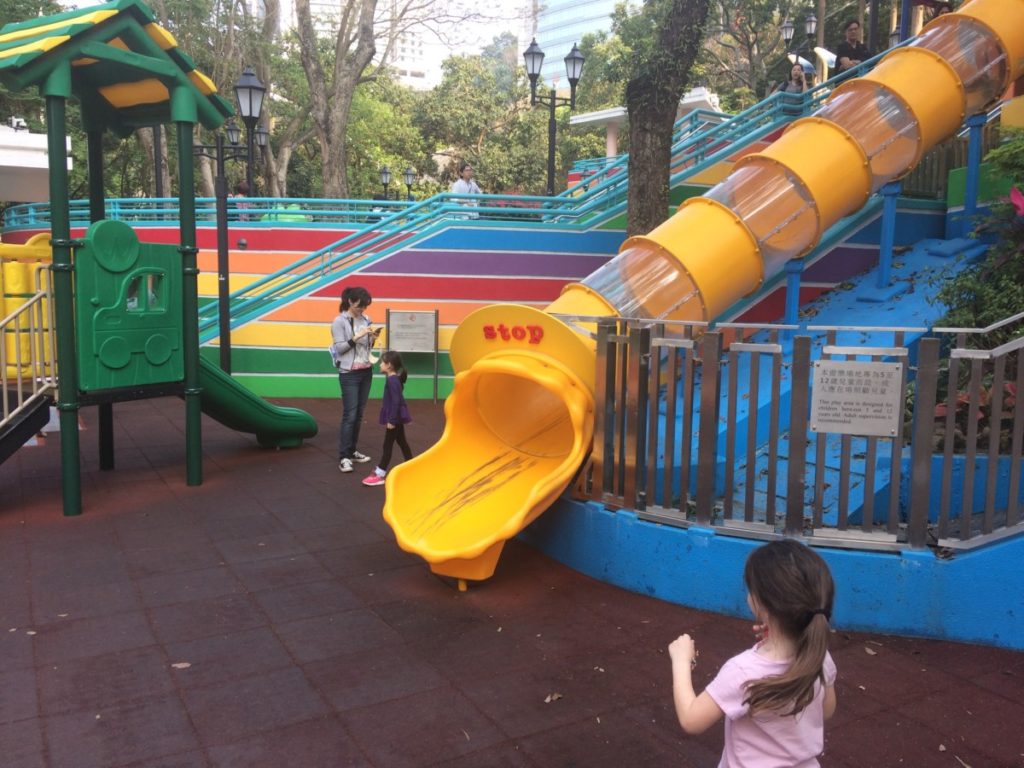 a young girl plays at the bottom of a slide at Hong Kong Playground Park