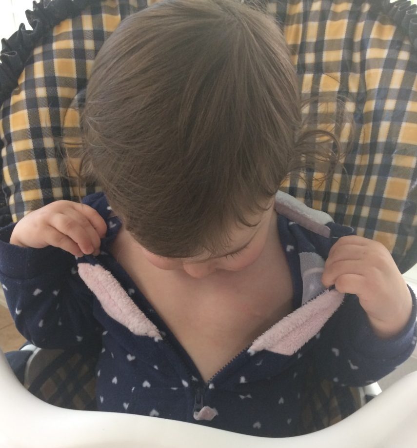 Toddler unzips their outfit to reveal chest