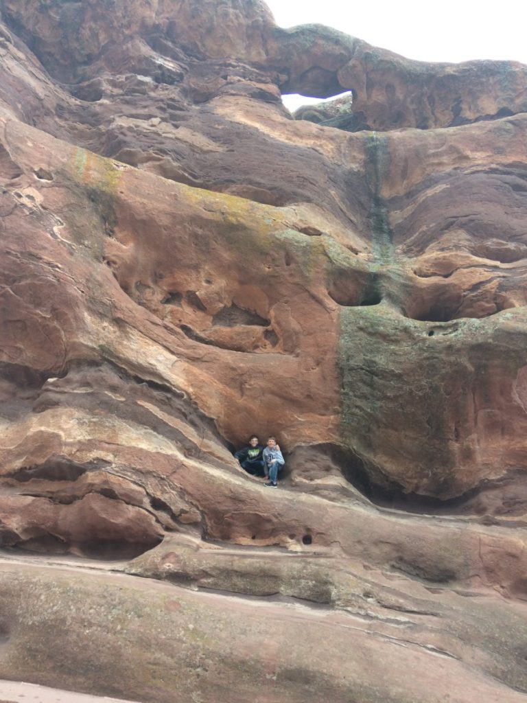 2 boys huddle in a rock cavity at Red Rocks Amphitheater