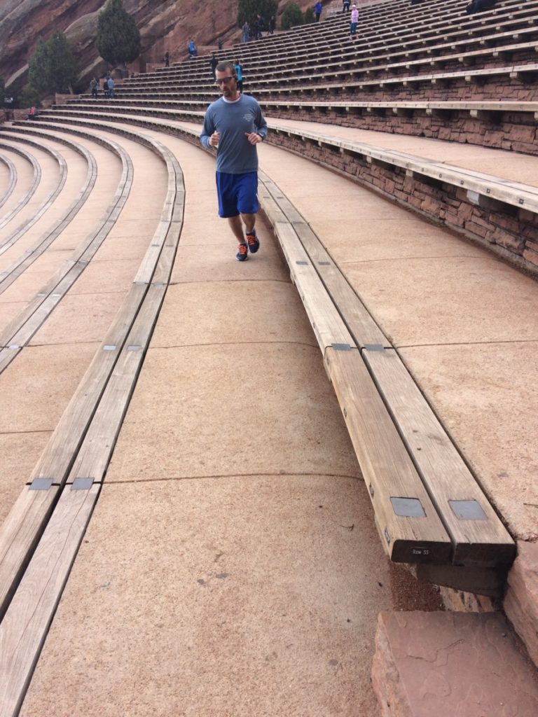 A man runs along the rows of seating at Red Rocks Amphitheater