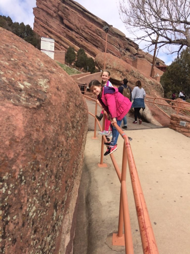 2 girls climb on the stair rails near the Red Rocks Amphitheater