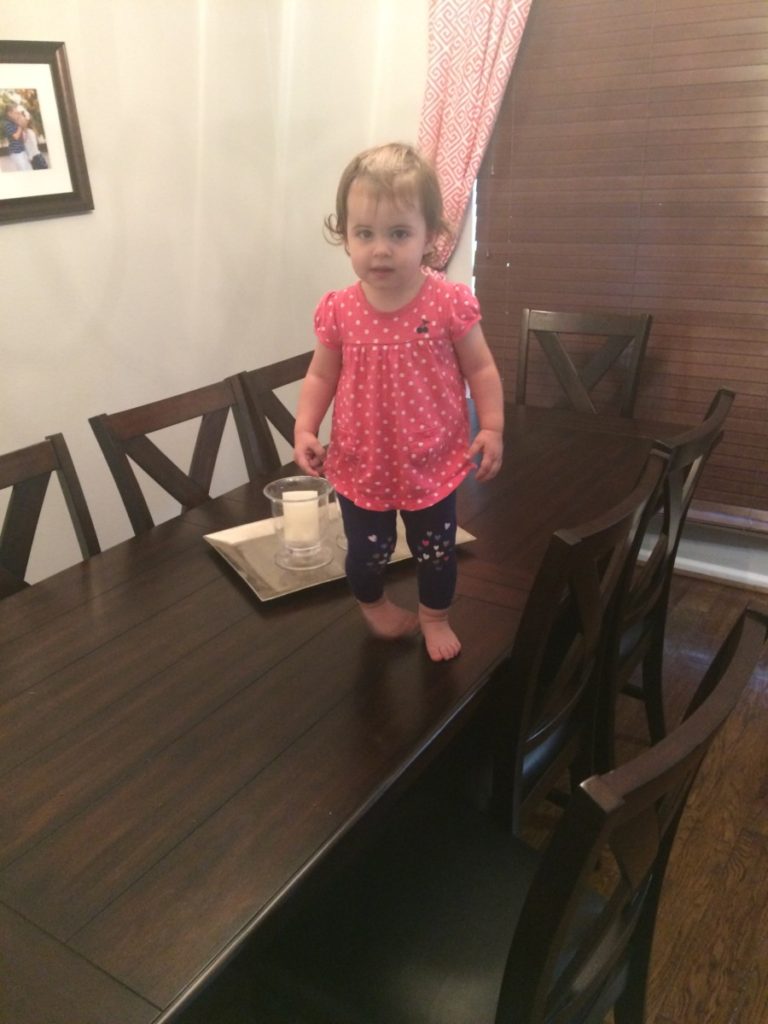 A toddler walks on the top of the table