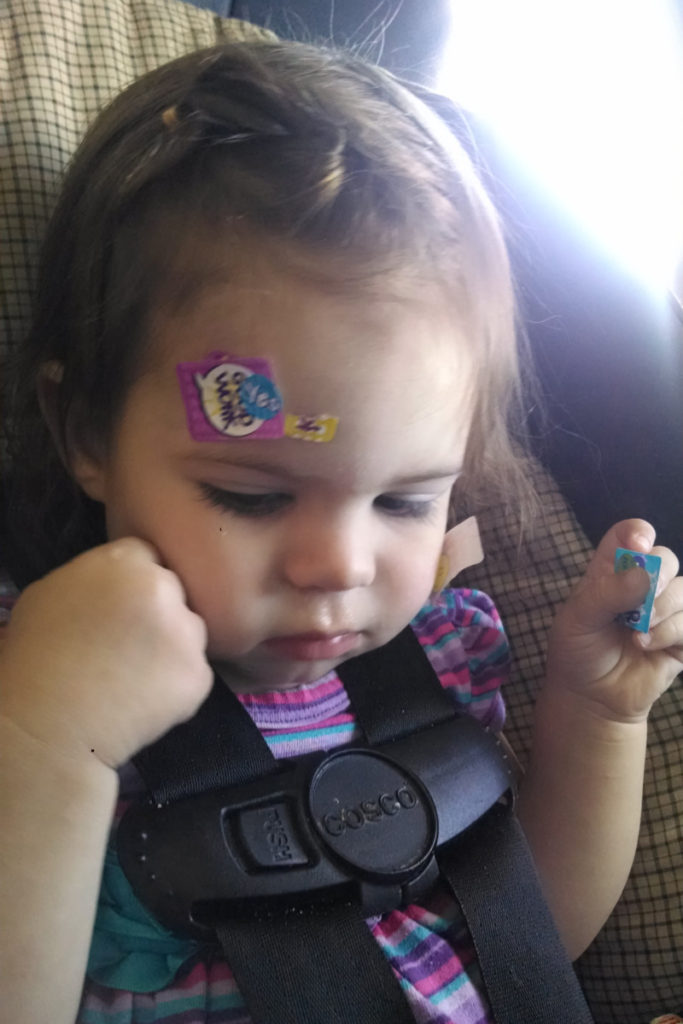 Toddler with stickers on her forehead and hands