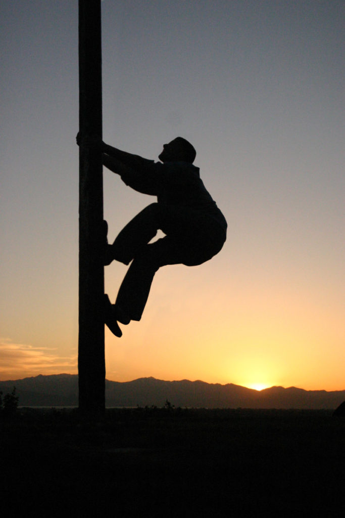 a silhouette climbing a pole in the sunset