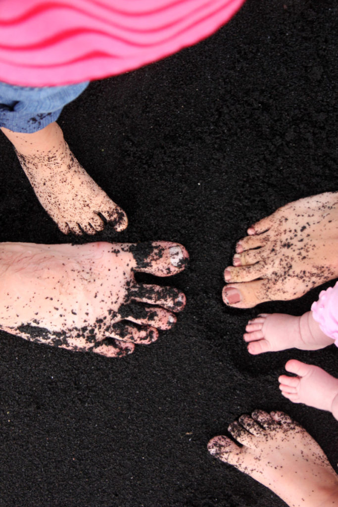 the feet of a family of 5, standing on black sand beach on the Big Island, Hawaii