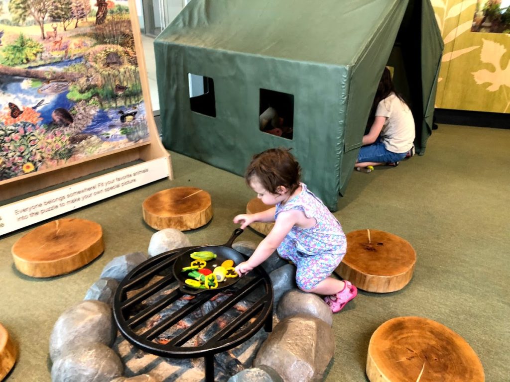 a toddler makes a fire at the Perot Museum camping area