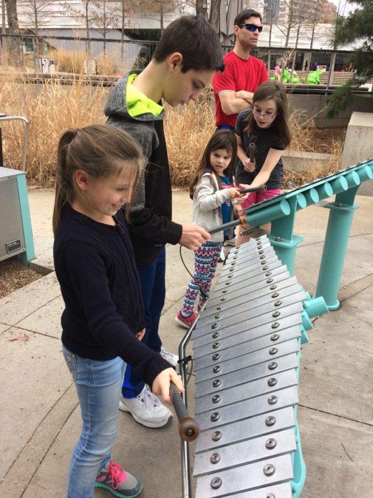 a young girls plays an xylopohone at the Perot Museum outdoor area