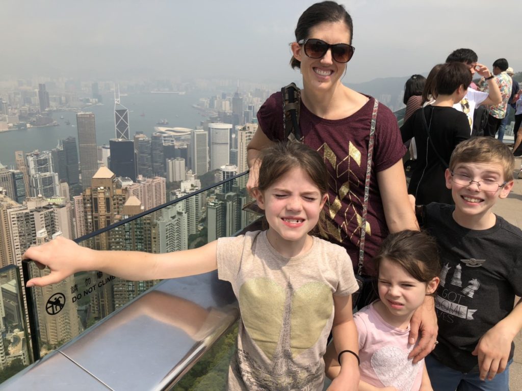 Mom and 3 kids at Victoria's peak in Hong Kong looking over the skyscrapers
