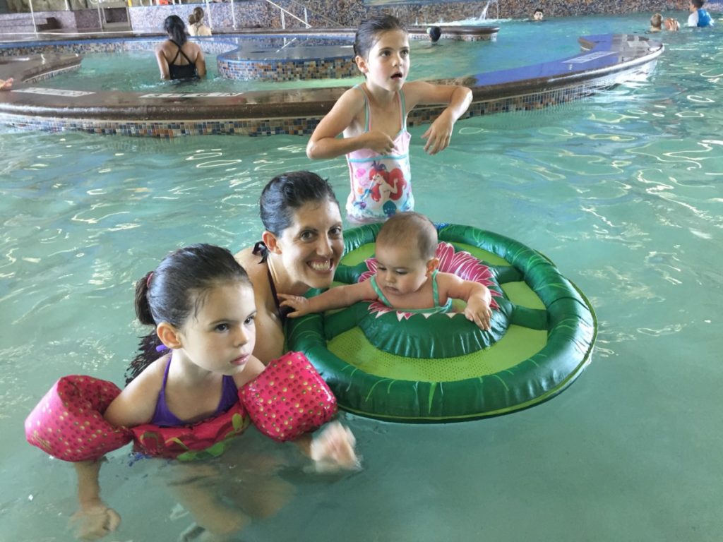 mom and 3 girls swimming in a pool