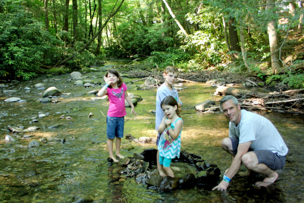 Dad with 3 kids plays in a creek