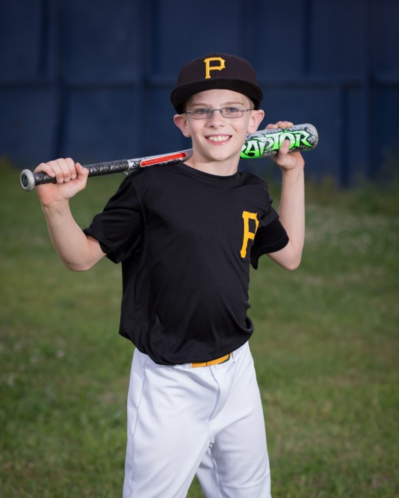 a boy in a black pirates baseball uniform