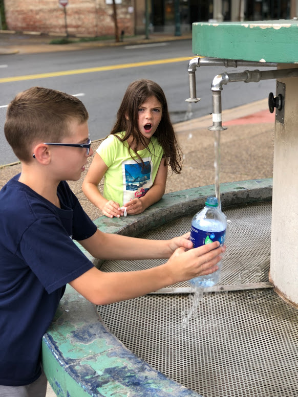 A young boy fills up a water bottle with thermal water at Hot Springs National Park