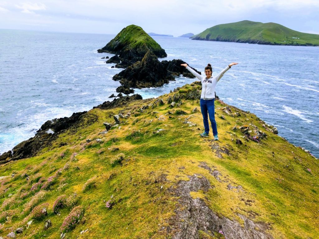 A woman stand showing the incredible view of the rocky and grassy Blasket Islands from Coumeenoole point on Dingle Peninsula, Ireland