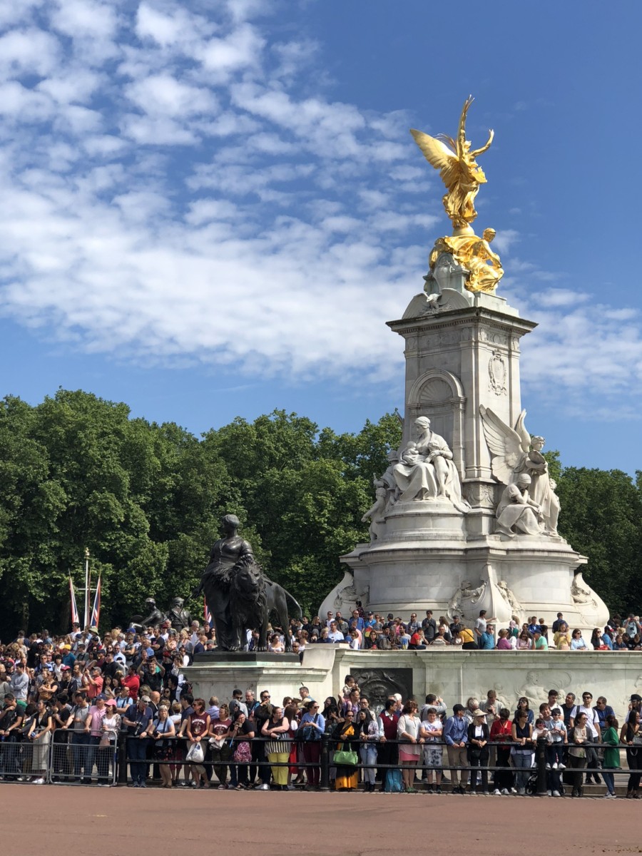 Crowds gather at the center statue in front of Buckingham Palace in London