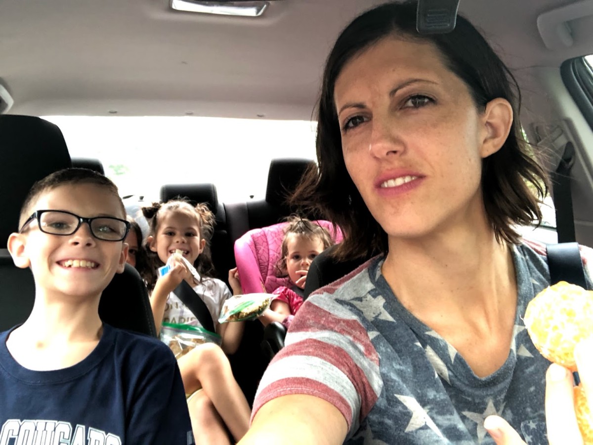 Mom and 4 kids eating picnic lunch in the car.