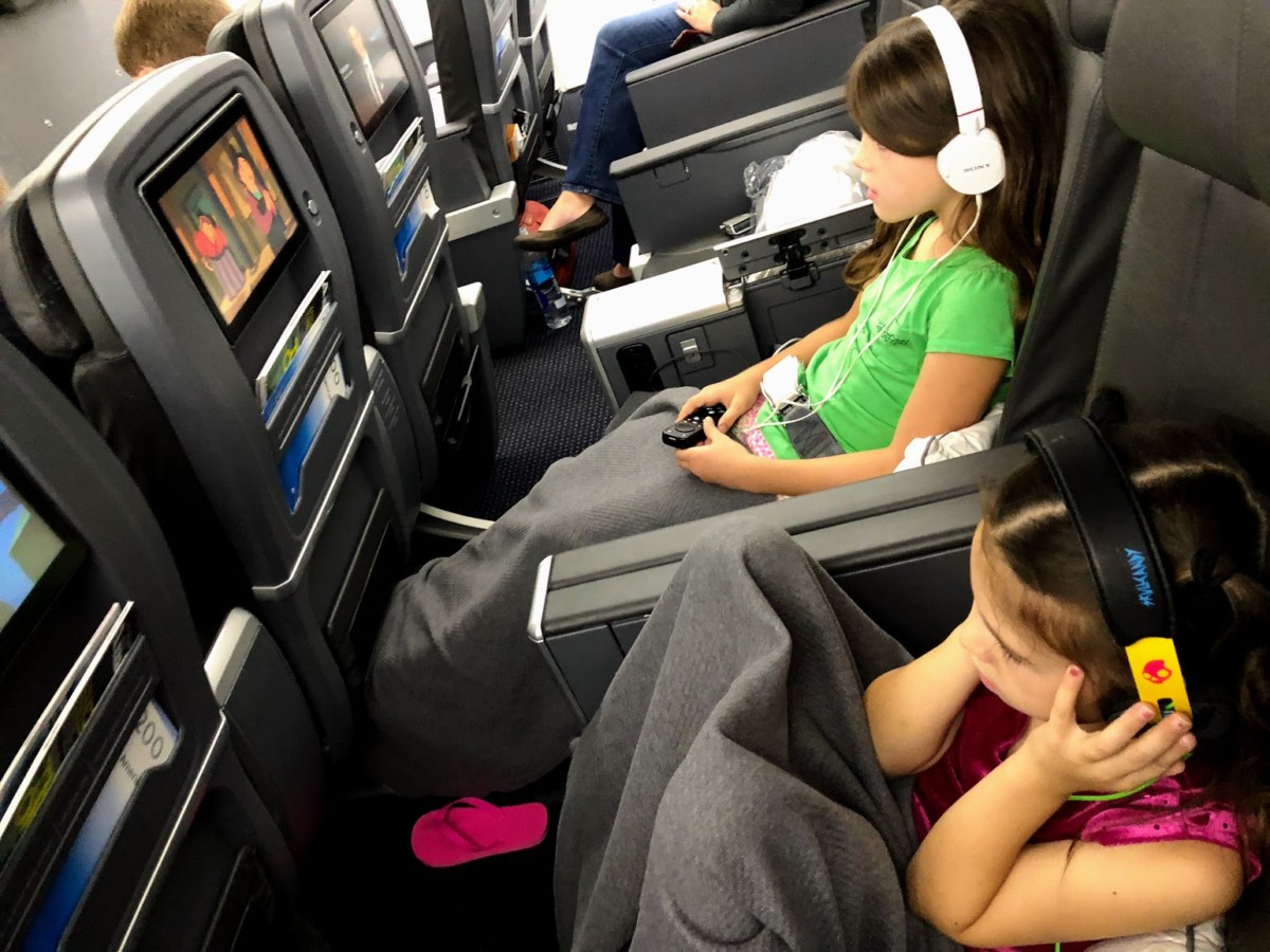 2 girls watch movies with headphones in Premium economy seats on American Airlines. 