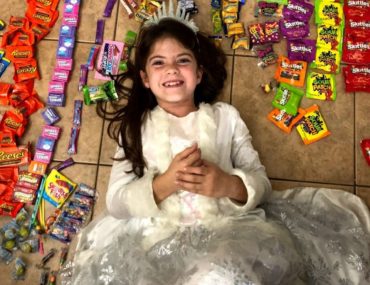 Girl lays in the middle of Her Halloween candy