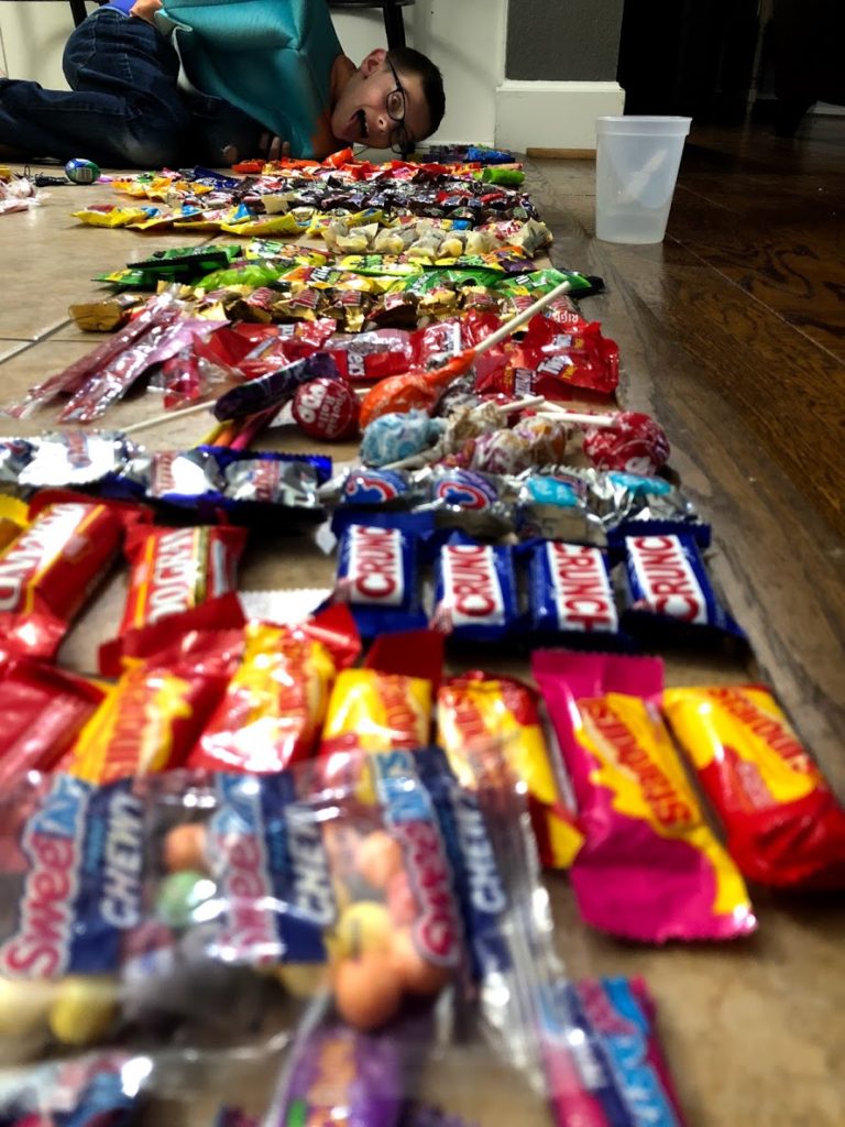 a boy behind his array of Halloween candy categorized by type