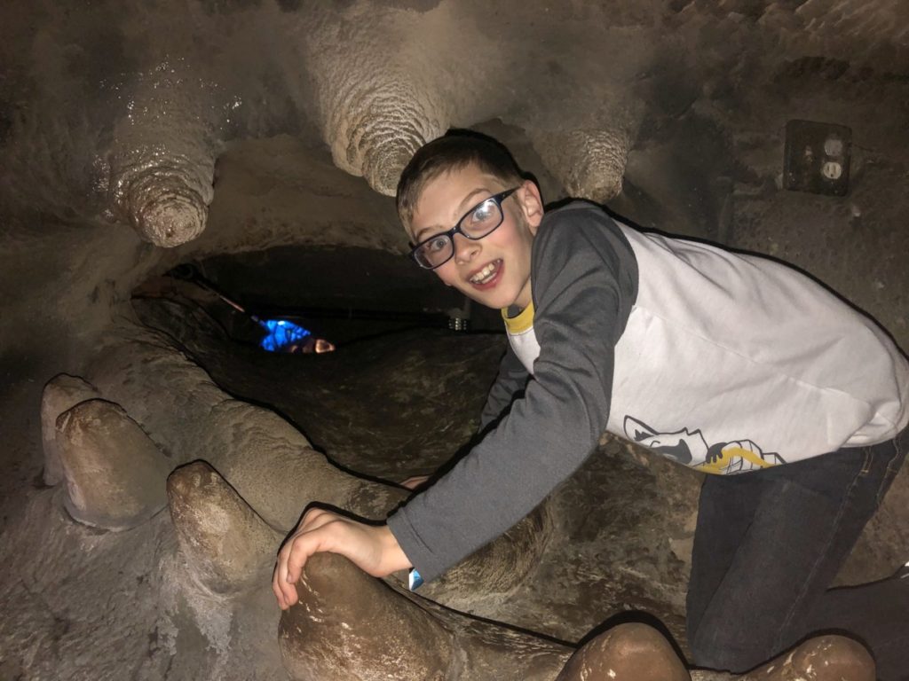 A Boy grins while crawling through the caves in the City Museum