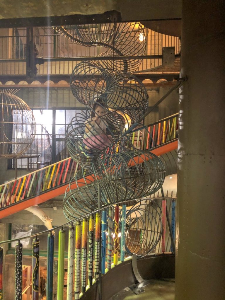 A girl climbing in a metal circular structure at the City Museum