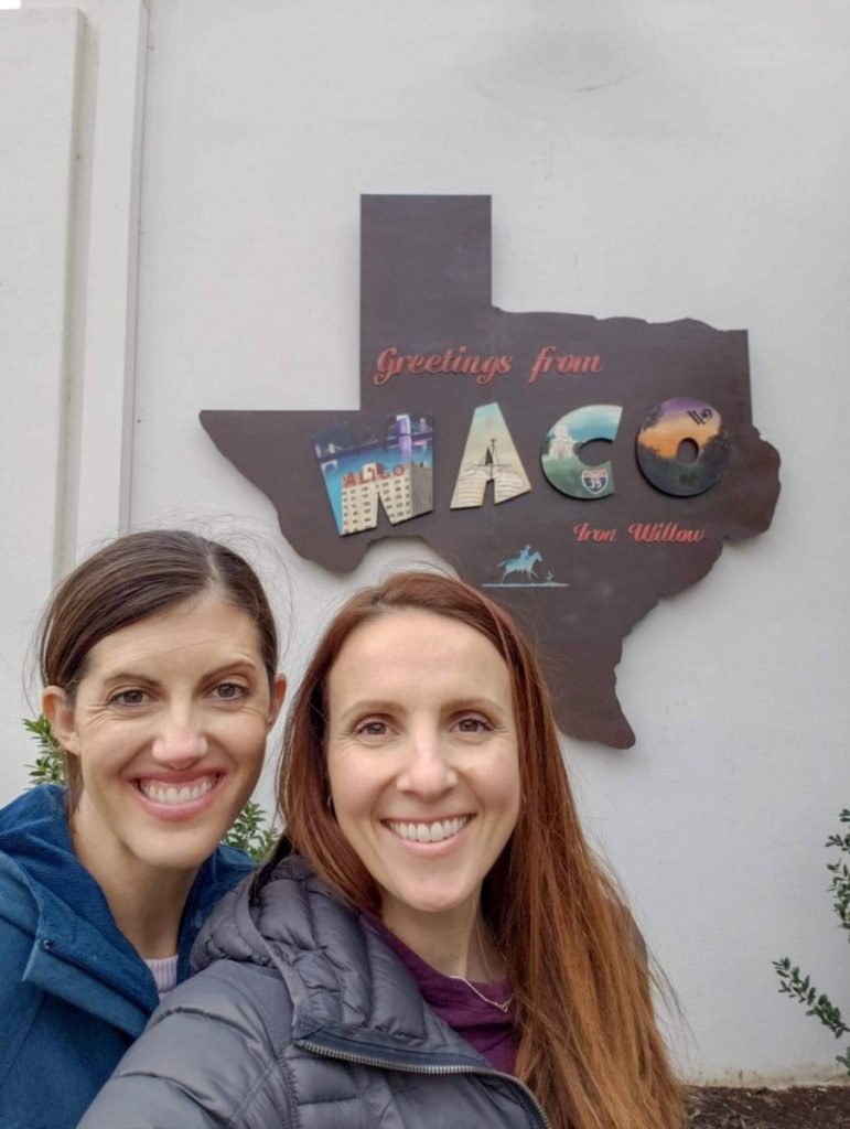 2 women in front of the greeting from Waco sign.