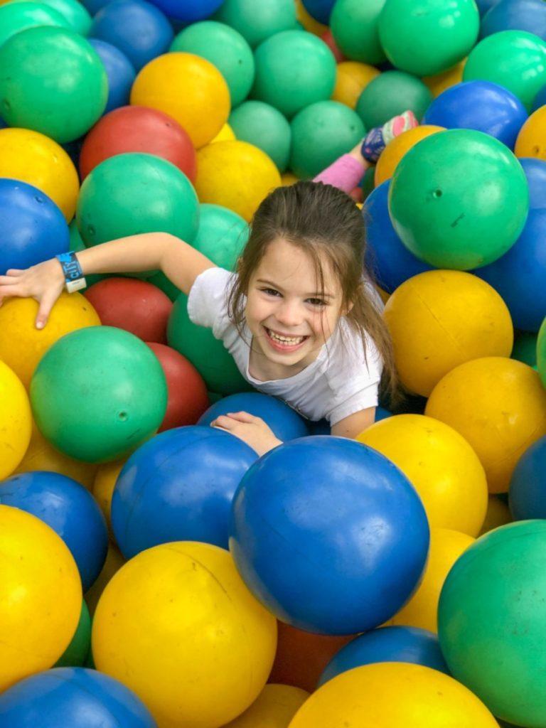 A young girl swims through blue, green and yellow balls at the City museum