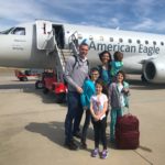 a Family of 6 stands on the tarmac in front of a small American Airlines Airplane