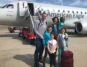 a Family of 6 stands on the tarmac in front of a small American Airlines Airplane