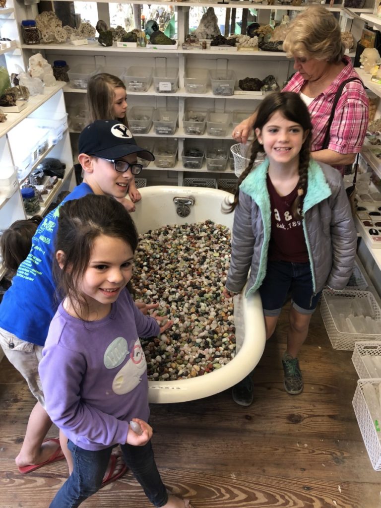 3 kids stand around Johnson's Rock shop Bathtub of Gemstones