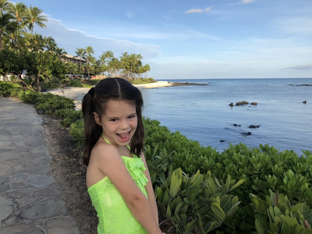 a girl smiles at the beach at Hilton Waikoloa.