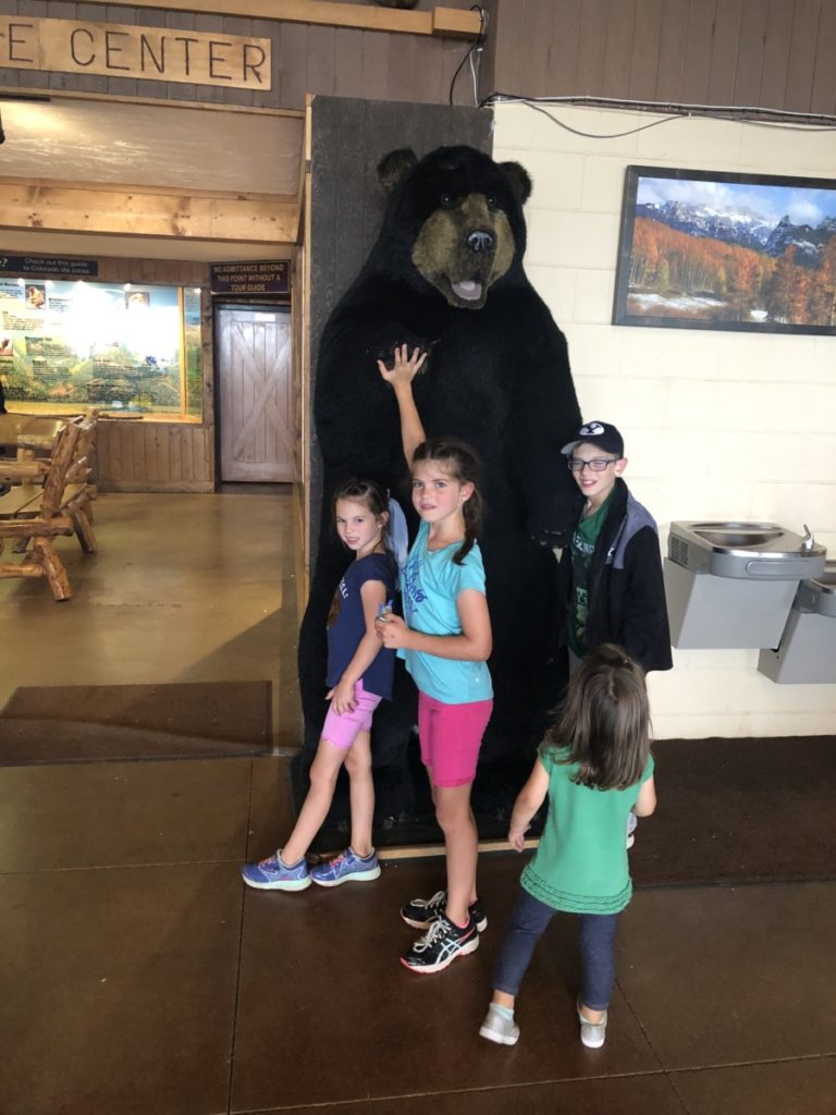 4 kids at the entrance of Cave of the Winds Discovery Tour with a 6-foot bear.