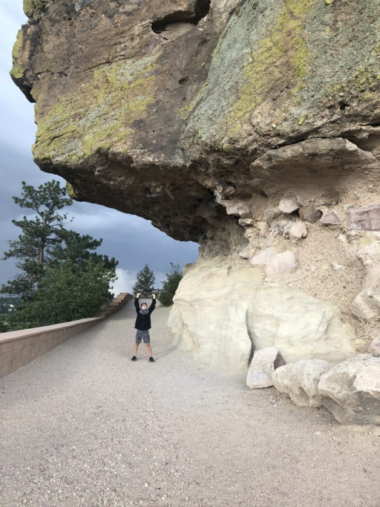 A young boy stands under an over hang at Castle Rock, Colorado