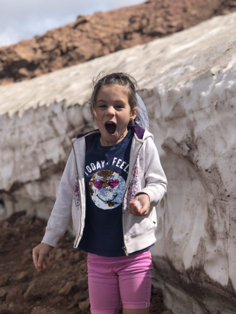 A young girl is in shock touching snow at Pikes peak in Colorado Springs with kids