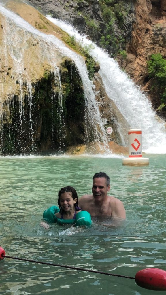 A Dad and Daughter smile together in the Water below Turner falls