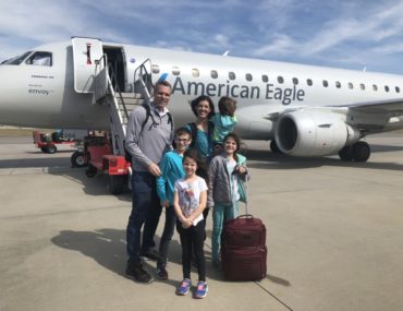 Family of 6 with luggage in Front of American Airlines plane