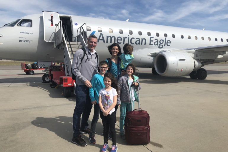 Family of 6 with luggage in Front of American Airlines plane