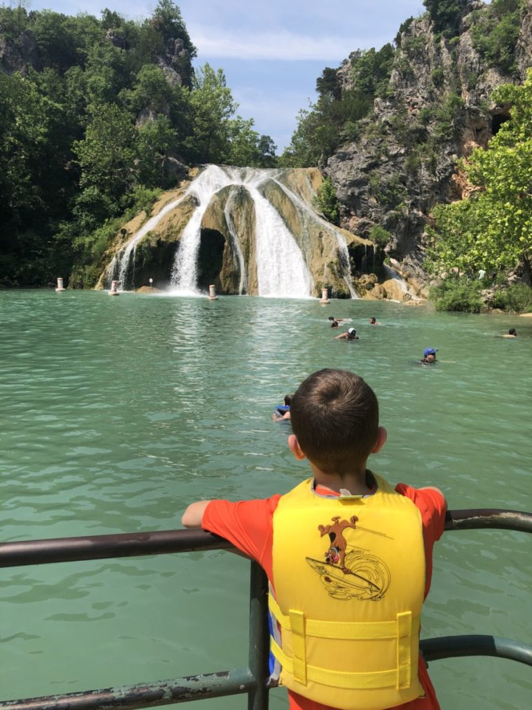 A boy looks on from the walkway to Turner Falls