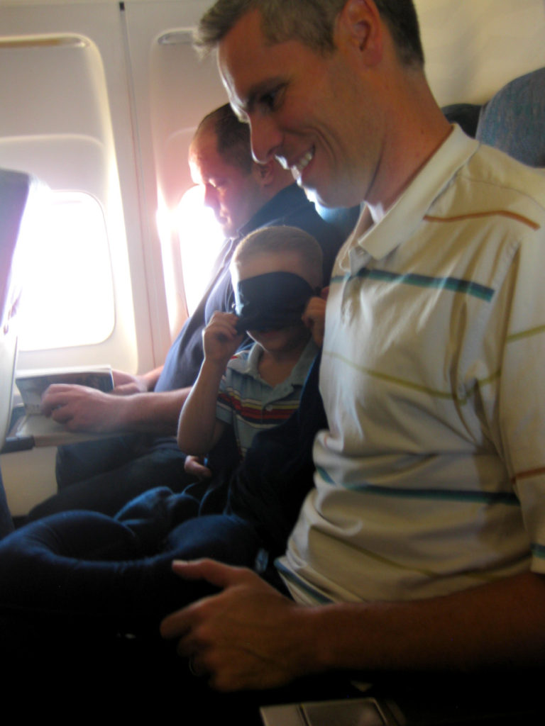 a boy wears a sleep mask on an airplane